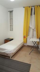 a bedroom with a bed and a yellow curtain at Chambres à PARIS in Ivry-sur-Seine