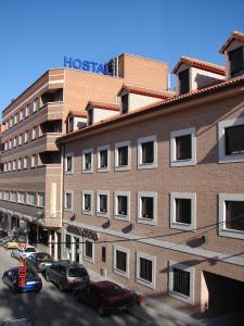 un edificio alto de ladrillo con coches estacionados frente a él en Hostal Goyma III, en San Fernando de Henares