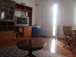 a living room with a table and a tv and a door at Casa das Merces in Angra do Heroísmo