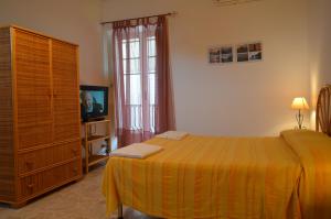 - une chambre avec un lit, une commode et une télévision dans l'établissement Case Vacanze Arcobaleno, à Lipari