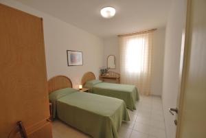 a hotel room with two beds and a window at Appartamenti Olivo - 100 mt dal mare con aria condizionata in Marina di Campo