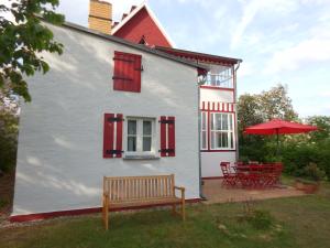 Casa blanca con ventanas rojas y banco en Ferienwohnungen Obstwiese & Sonnenschein en Himmelpfort