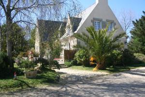 a house with a pointed roof and a palm tree at Chez Renée et Raynal B&B in Plounévez-Lochrist