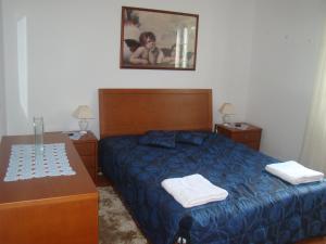 a bedroom with a blue bed and two night stands at Casa das Merces in Angra do Heroísmo