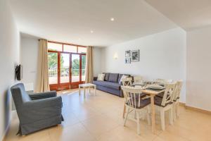 ein Wohnzimmer mit einem Tisch und einem blauen Sofa in der Unterkunft Bagari Apartments Camp de Mar in Camp de Mar