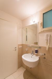 a white bathroom with a sink and a mirror at Wally Residence in Rimini