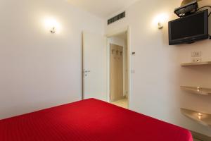 a room with a red bed and a flat screen tv at Wally Residence in Rimini