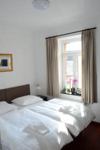 Un dormitorio con una gran cama blanca y una ventana en Le Baron Apartments, en Stavelot
