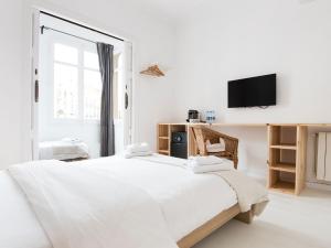 a white bedroom with a large bed and a tv at Bruc & Bruc in Barcelona