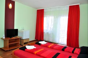 クルジュ・ナポカにあるCasa Otiliaのベッドルーム1室(ベッド2台付)、赤いカーテン付きの窓が備わります。