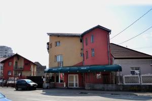 ein rotes Gebäude mit blauer Markise auf einem Parkplatz in der Unterkunft Casa Otilia in Cluj-Napoca