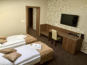 a hotel room with two beds and a desk and a television at Grillbar Penzion & Restaurant in Spišská Nová Ves