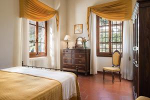 1 dormitorio con 1 cama, 1 silla y ventanas en Casa Vacanze Villa il Castellaccio, en Lucolena in Chianti