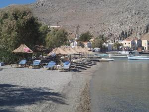 a group of chairs and umbrellas on a beach at "STELIOS & GALINI" in Symi