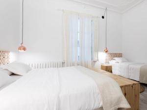 a white bedroom with two beds and a window at Bruc & Bruc in Barcelona