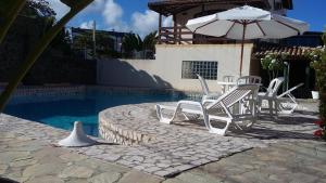 a group of chairs and an umbrella next to a pool at Pousada Porto Villas in Lauro de Freitas