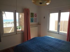 a bedroom with a blue bed and two windows at Surf House in Artemida