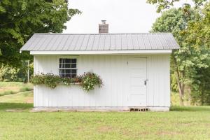 a white shed with a window and flowers on it at Grandma's Cottage Sleeps 10 in Columbia