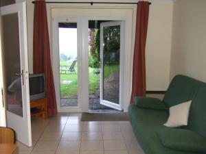 a living room with a couch and a sliding glass door at L'Horizon Studios & Apparts in Malmedy