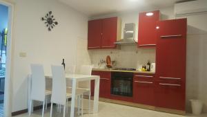 a kitchen with red cabinets and a white table and chairs at Apartments Sorgo in Novigrad Istria