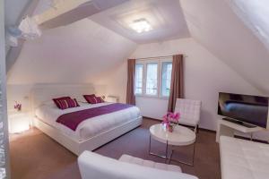 een witte slaapkamer met een bed en een televisie bij Hotel Relais Saint Jean Troyes in Troyes