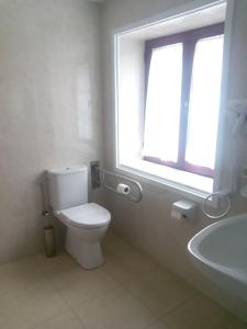 baño con aseo y lavabo y ventana en Hotel Las Grandas, en Vistalegre