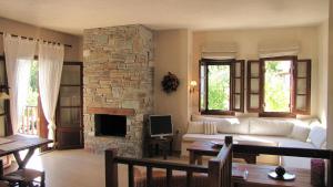 a living room with a white couch and a stone fireplace at EL Villa Pelion in Chorto