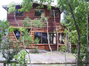 ein Holzhaus mit Bäumen davor in der Unterkunft Turismo Montaña II in La Ensenada
