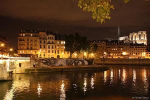 a city at night with a river and buildings at Le Voyage En Isle in Paris