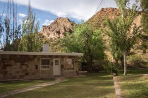 un pequeño edificio de piedra frente a una montaña en Bosque Divino Cabañas & Suites, en Valle Grande
