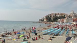 una spiaggia con molta gente e l'oceano di Case vacanze Mirko IMPERIA BORGO MARINA a Imperia