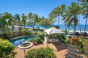 a swimming pool with a table and chairs and the beach at Trinity Waters Boutique Beachfront in Trinity Beach