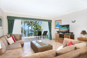 a living room with a couch and a television at Trinity Waters Boutique Beachfront in Trinity Beach