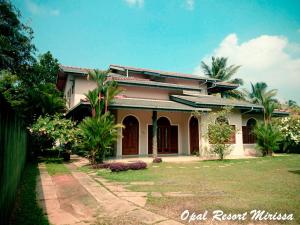 a house with palm trees in front of it at Opal Mirissa in Mirissa