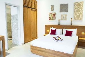 1 dormitorio con 1 cama blanca grande con almohadas rojas en Villa Angela, en Seminyak