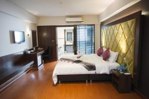 a bedroom with a bed and a desk and a television at Grand Pink Hotel Hatyai in Hat Yai