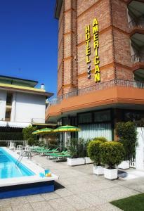 un hotel con piscina di fronte a un edificio di Hotel American a Lido di Jesolo