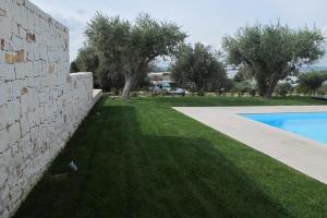 a yard with a stone wall and a swimming pool at Kinanto Bioresort in Ispica