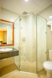 a glass shower in a bathroom with a sink and a toilet at Red Palace Hotel in Da Nang