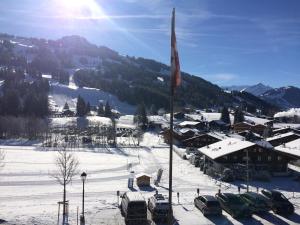un village dans la neige avec un drapeau sur un pôle dans l'établissement Chalet Mutzli, à Gstaad