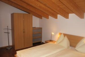ベットマーアルプにあるWakatipu-Lodgeのベッドルーム1室(ベッド1台付)、木製キャビネットが備わります。