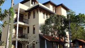 a white building with trees in front of it at Park Lane 88 Apartments in Negombo