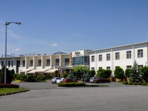 un gran edificio blanco con coches aparcados en un aparcamiento en Hotel Restauracja Autos, en Solec Kujawski