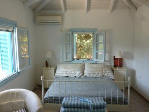ein Schlafzimmer mit einem Bett und zwei Fenstern in der Unterkunft Lemon Tree Cottage in Finikounda