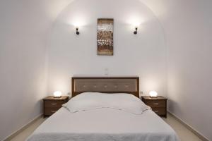 um quarto com uma cama branca e duas mesas de cabeceira em Unique Leta em Fira
