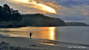 a person standing on the beach at sunset at Hôtel de la Baie in Crozon