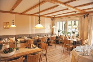 a restaurant with wooden tables and chairs and windows at Wein & Gästehaus Rosenlay in Lieser
