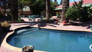 a swimming pool in a courtyard with trees at Lamberts Bay Hotel in Lambertʼs Bay