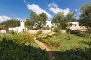un giardino fiorito e una casa sullo sfondo di Casa Murredda by BarbarHouse a Ceglie Messapica