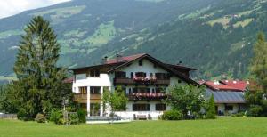 a large house with a balcony in a field at Gästehaus Brindlinger in Zell am Ziller